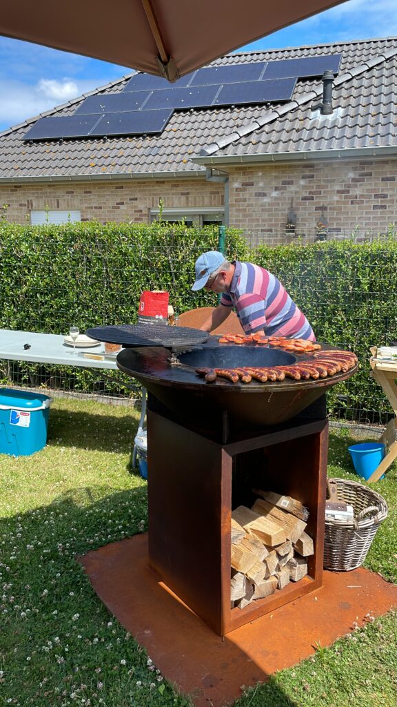 Cortenstaal BBQ met houtopslag, gemaakt door Parmentier Mechanical Service, in gebruik in een tuin